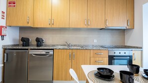 Una cocina moderna con armarios de madera, electrodomésticos de acero inoxidable y un comedor con mesa para cuatro.
