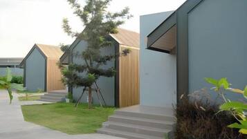 Un bâtiment moderne doté d’un toit plat, d’un petit arbre au centre et d’un chemin pavé menant à l’entrée.