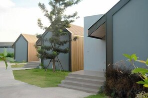 A modern building with a flat roof, a small tree in the center, and a paved walkway leading to the entrance. - The Posh Khao Kho (Khao Kho)