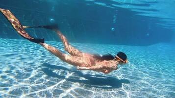 A person swimming underwater in a pool.