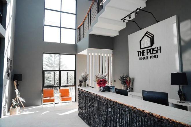 A modern reception area with a high ceiling, large windows, and a reception desk with a logo.