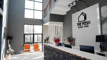 A modern reception area with a high ceiling, large windows, and a reception desk with a logo.