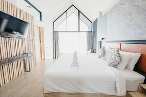 Moderni hotellihuone, jossa on sänky, televisio ja suuri ikkuna.