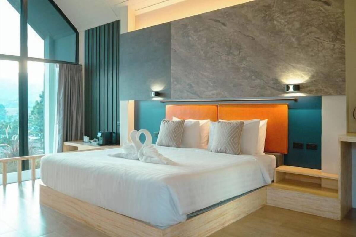 Ein modernes Hotelzimmer mit einem großen Bett, Blick ins Freie und einem besonderen Wanddesign.
