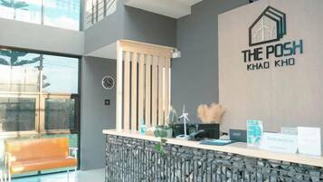 Un espace d’accueil au design moderne, comprenant un comptoir de réception, une horloge et un logo sur le mur.