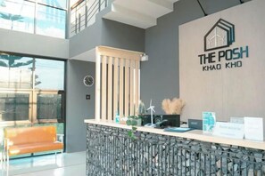 A reception area with a modern design, including a reception desk, a clock, and a logo on the wall. - The Posh Khao Kho (Khao Kho)