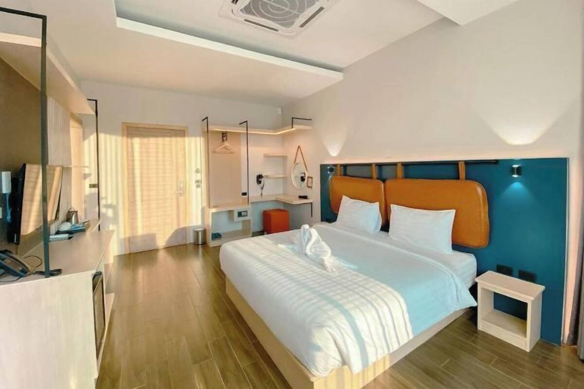 Ein modernes Hotelzimmer mit einem großen Bett, einem Nachttisch, einem Spiegel und einem Kleiderschrank.