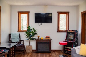 A living room with a television, a plant, a fireplace, and a video game console.