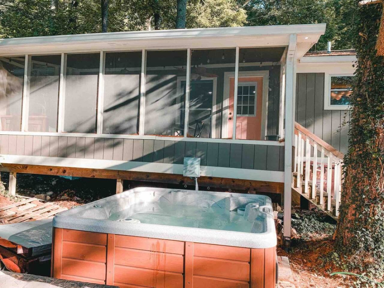 A two-story house with a covered porch, a hot tub, and a staircase leading to the upper level.