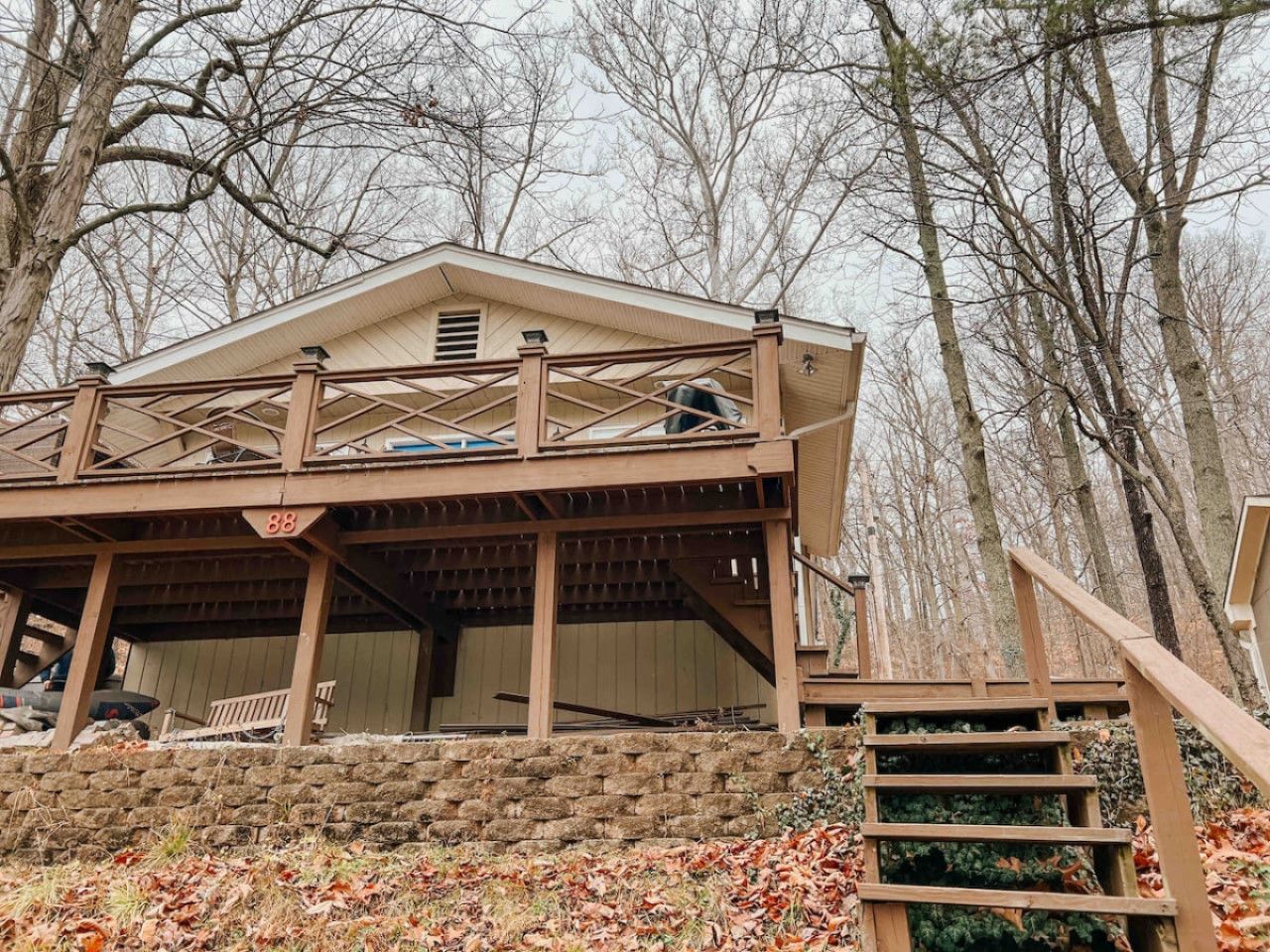 A two-story wooden cabin with a covered porch and a staircase leading to the upper level.