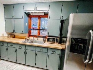 A kitchen with grey cabinets, a stainless steel refrigerator, and a window with a view of the outside. - Two lakefront cabins next door (Martinsville)