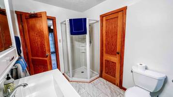 Une salle de bain avec un lavabo blanc, des toilettes et une douche à parois de verre.