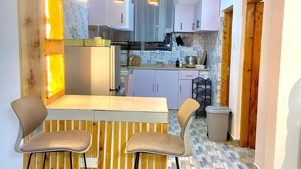 Una cucina moderna con una parete decorata in legno, un angolo bar con sgabelli e luci a sospensione.