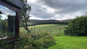 A view from a window overlooking a green field with a fence, a tree, and a lamp post. - The Mill - Amazing spacious mountain escape in Speyside & the Cairngorms (Ballindalloch)
