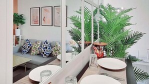 A modern living room with a sofa, coffee table, and large windows. - Chic 2-bedroom condo with AC, WiFi in enchanting Parañaque (Parañaque)