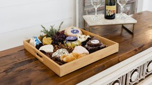 A wooden tray with various cheeses, fruits, and nuts on a wooden table.