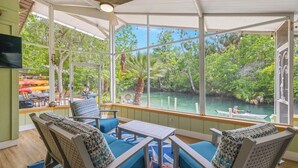 A covered outdoor seating area with a view of a river and greenery. - Stay directly on crystal clear waters of Weeki Wachee River with your own beach! (weekiwachee)