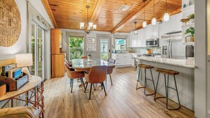 A modern kitchen with wooden ceiling beams, white cabinets, and a central island with stools. - Stay directly on crystal clear waters of Weeki Wachee River with your own beach! (weekiwachee)