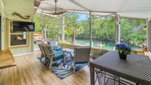 A covered outdoor area with a dining table, chairs, and a view of a river. - Stay directly on crystal clear waters of Weeki Wachee River with your own beach! (weekiwachee)