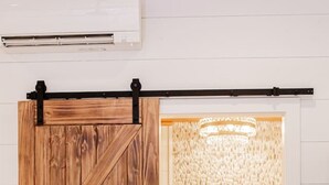 Un baño rústico con puerta de madera, una bañera y cortina de ducha texturizada.