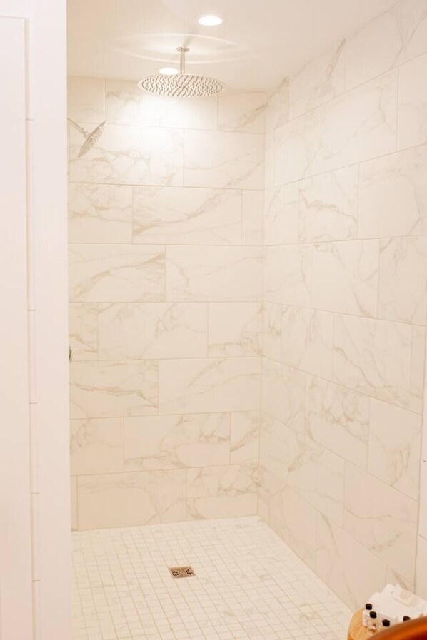 Ducha con azulejos de mármol blanco y un aplique de techo.