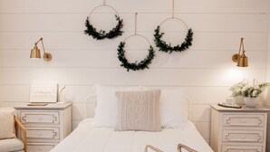 Un dormitorio con una cama, dos mesitas de noche, una mesilla auxiliar, una silla y tres apliques de pared.