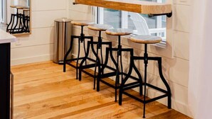 A kitchen with wooden beams, a window, and bar stools.