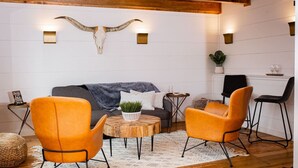 A cozy living room with a gray sofa, orange chairs, a wooden coffee table, and a large wall-mounted skull decoration.