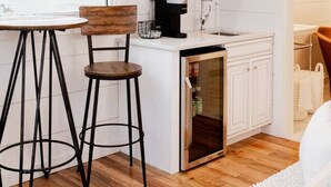 Cocina compacta con techo de madera, armarios blancos, un refrigerador pequeño y ventana con vista al agua.