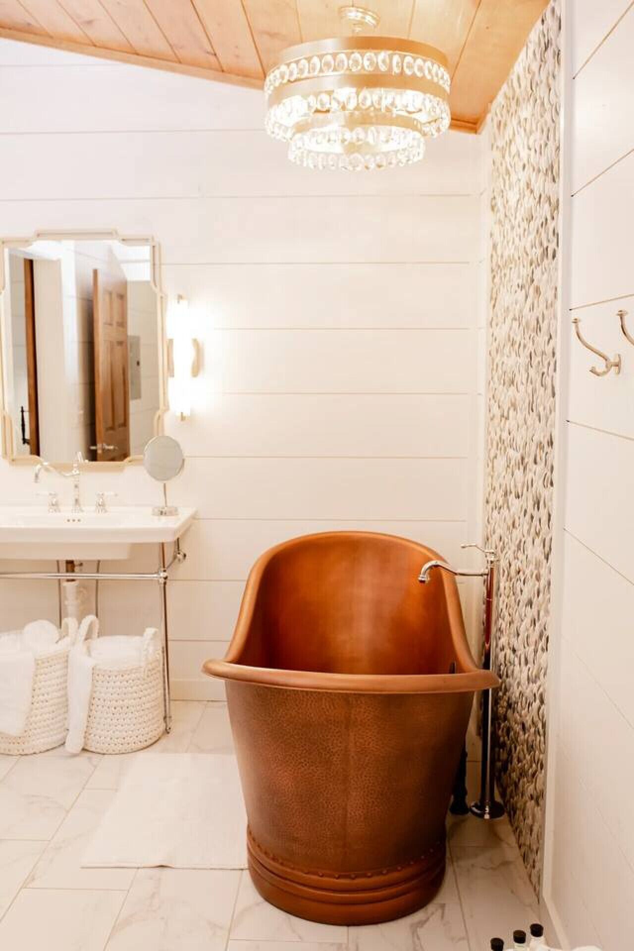 A bathroom with a freestanding bathtub, a vanity with a mirror, and a chandelier.