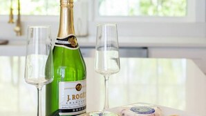 A table with a bottle of J. ROYER champagne, two glasses, and a plate with cheese and crackers. - The Cottage, Rusted Route Farms (Jackson)
