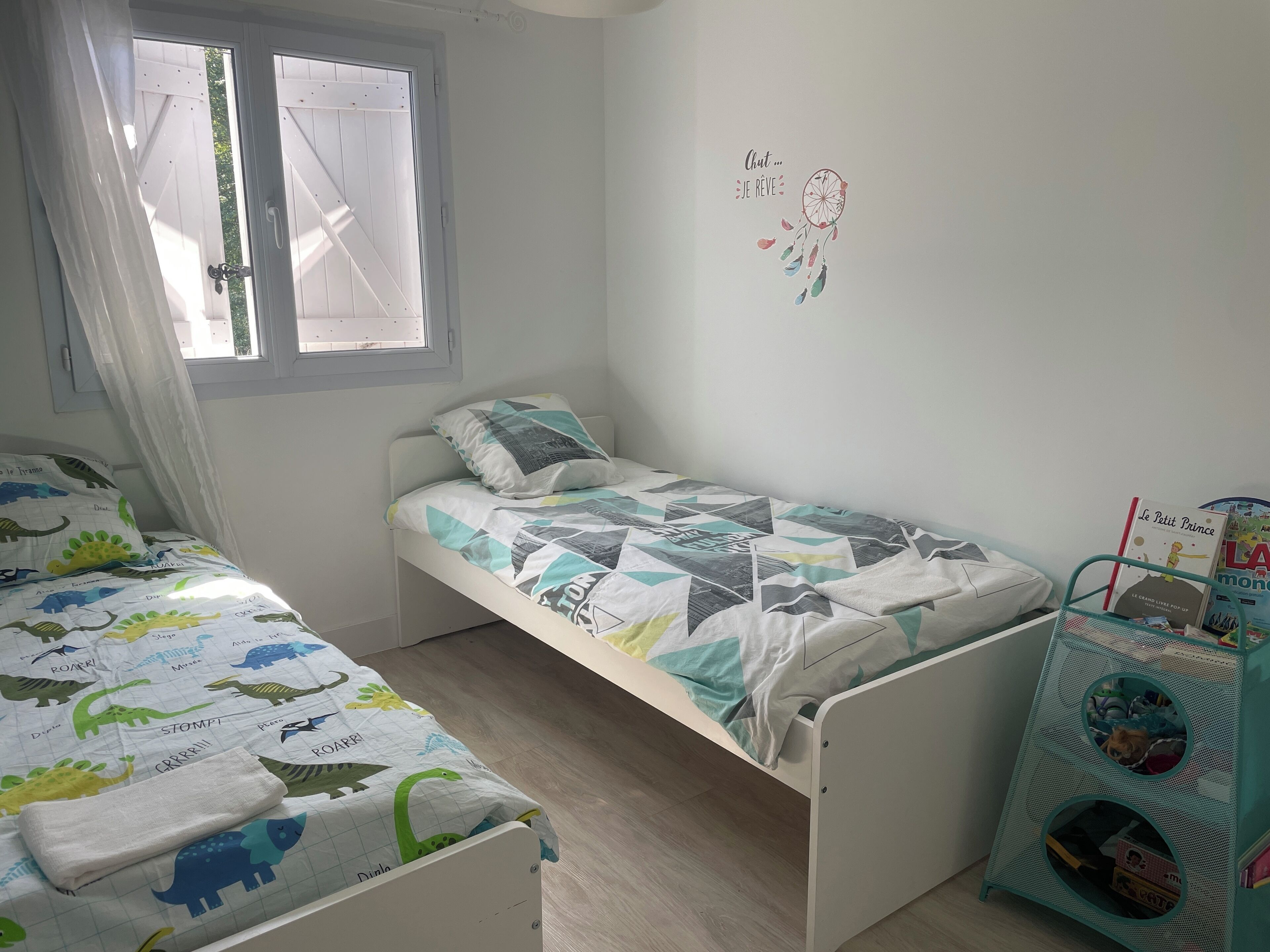 Ein Kinderzimmer mit Etagenbett, kleinem Schreibtisch und einem Fenster mit Vorhängen.