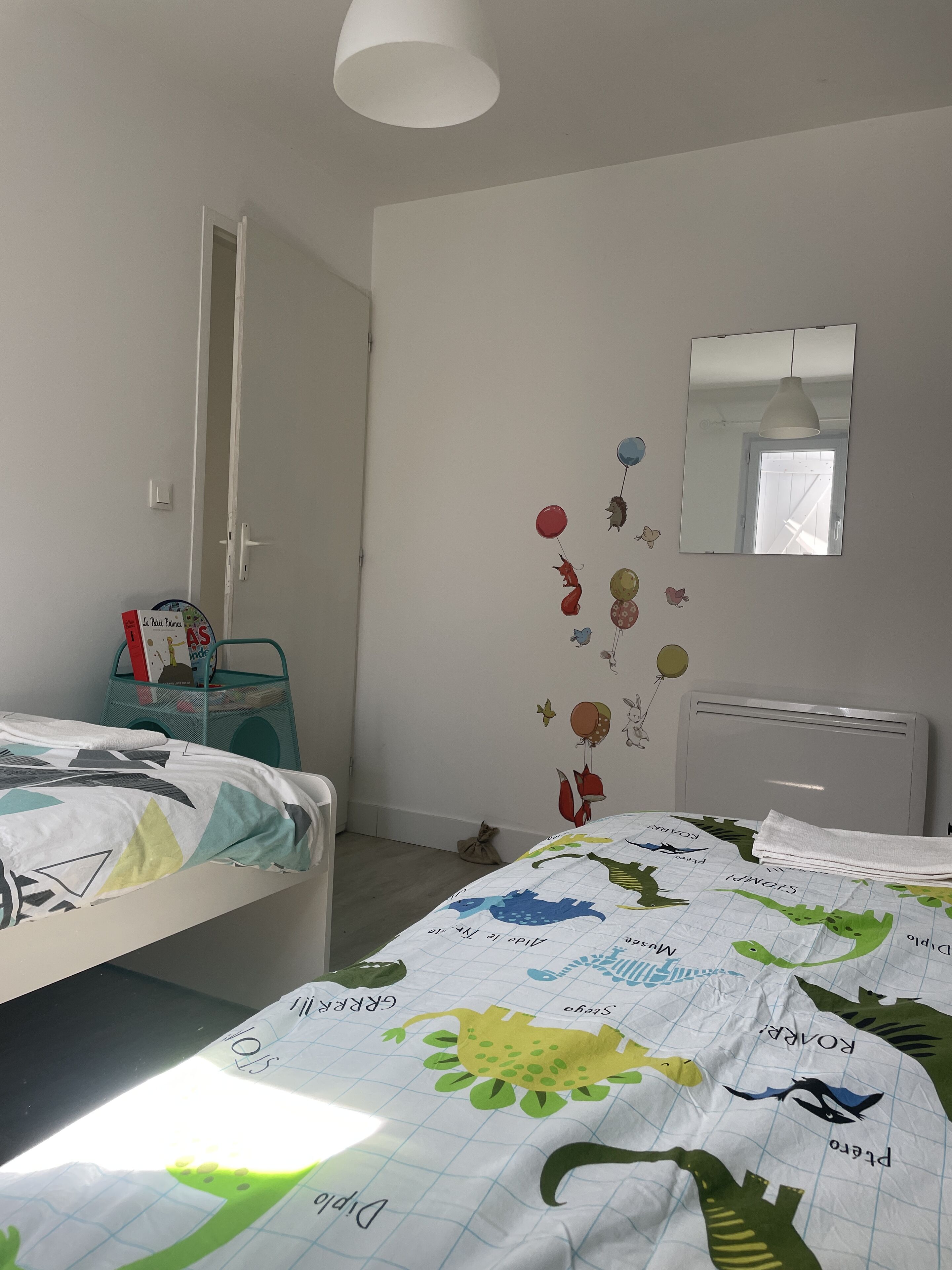 A bedroom with two beds, a wall-mounted mirror, and a window.