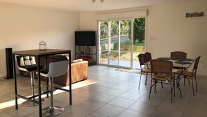 Una habitación amplia con una mesa de comedor, sillas, un sofá y un televisor.