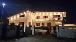 Een gebouw met twee verdiepingen en een hek, verlicht door buitenverlichting.