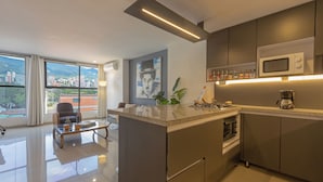 Una cocina moderna con una isla central, electrodomésticos de acero inoxidable y vistas a la ciudad a través de amplios ventanales.