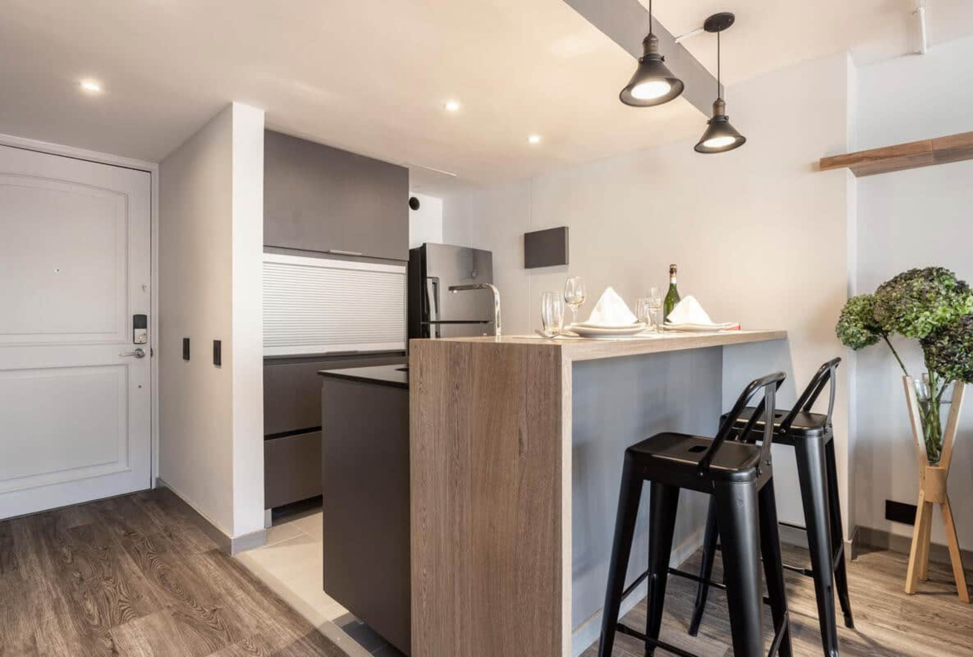 A modern kitchen with a central island, bar stools, and a small bar area.
