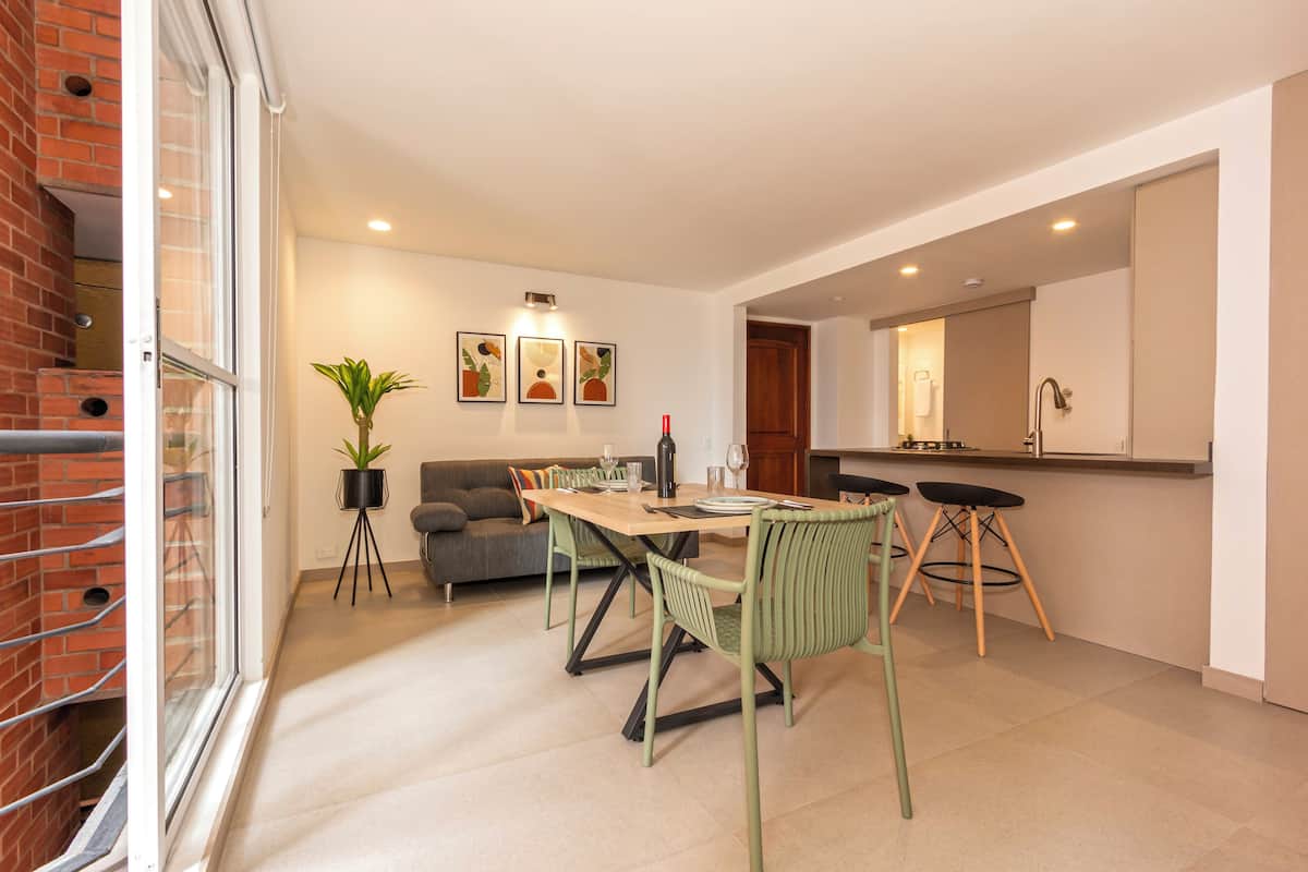 Une cuisine moderne avec un coin repas, comprenant un mur en briques, un canapé, une table à manger avec des chaises et une plante en pot.