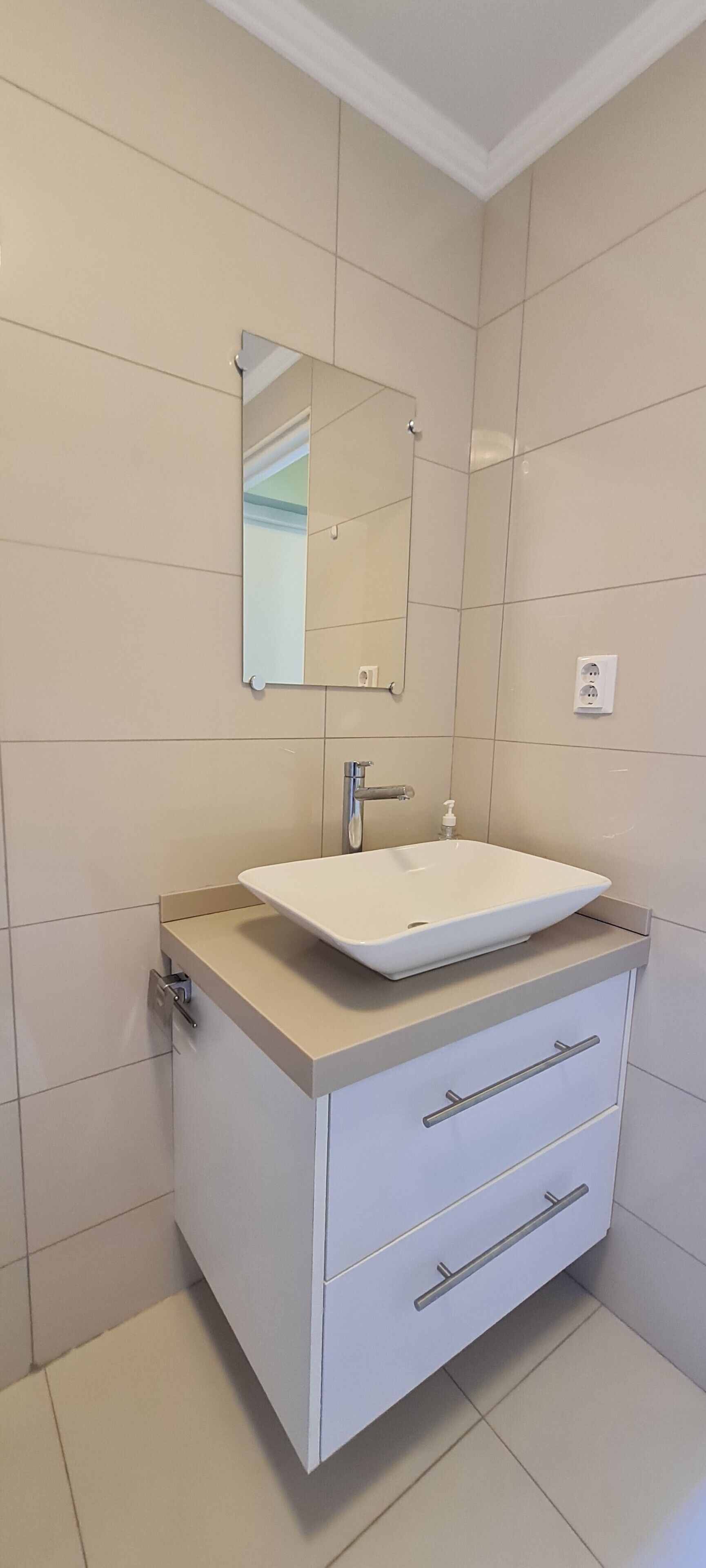 A bathroom with a white sink, a mirror, and a cabinet with drawers.