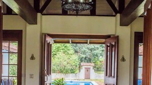 Un patio cubierto con vista a la piscina, una mesa de madera y piso de baldosas.