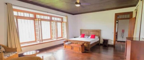 A bedroom with a wooden bed, a small table, and a window with curtains. - A Family Estate for the Perfect Vacation   (Parrita)