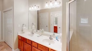 Une salle de bain avec deux lavabos, un grand miroir et un espace douche.