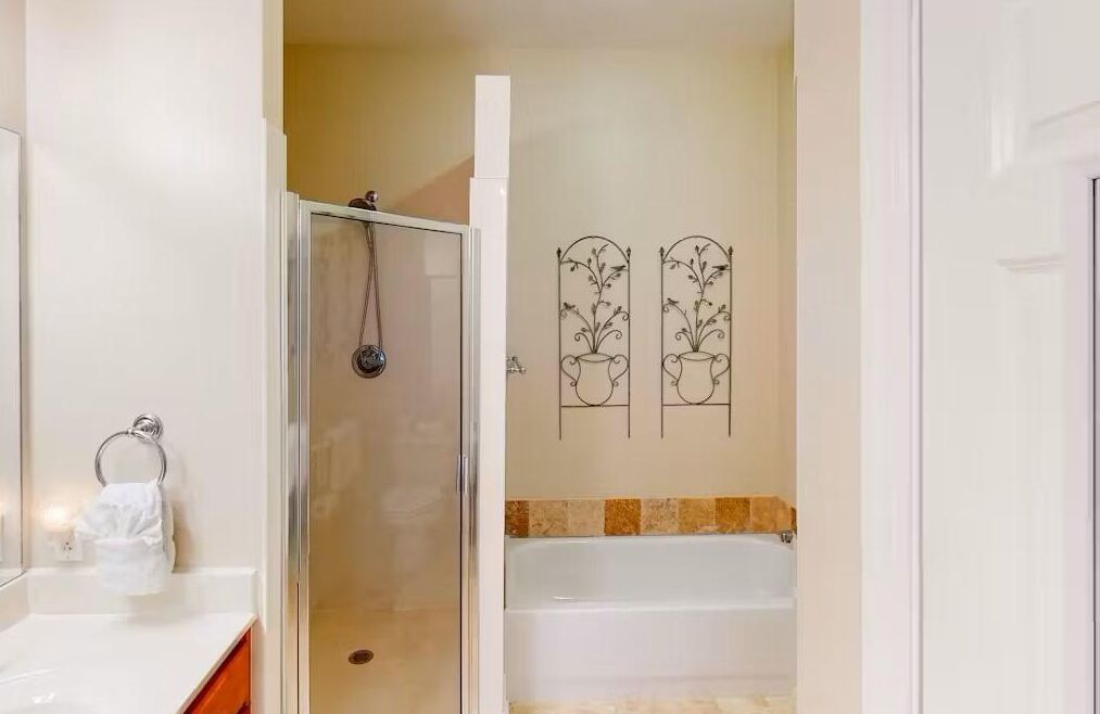 Un baño con ducha de vidrio, una bañera blanca y un perchero para toallas.