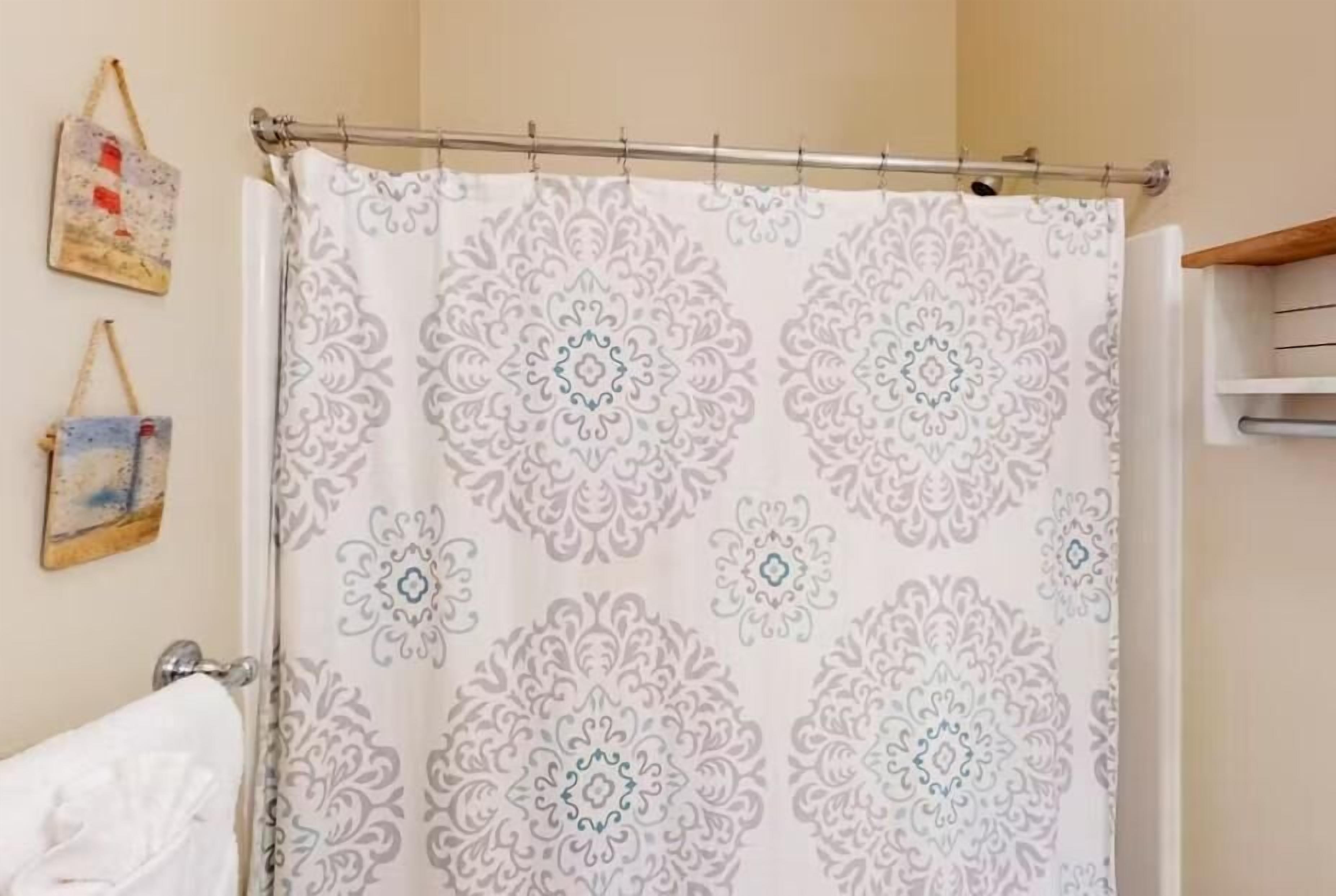 Une salle de bain avec un rideau de douche à motifs, un porte-serviettes et une serviette accrochée au mur.