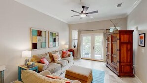 Un salon comprenant un ensemble de canapés, un meuble en bois et un ventilateur de plafond.