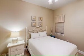 A bedroom with a bed, bedside tables, a lamp, and wall decorations. - Seagrove Highlands 1304 (Santa Rosa Beach)