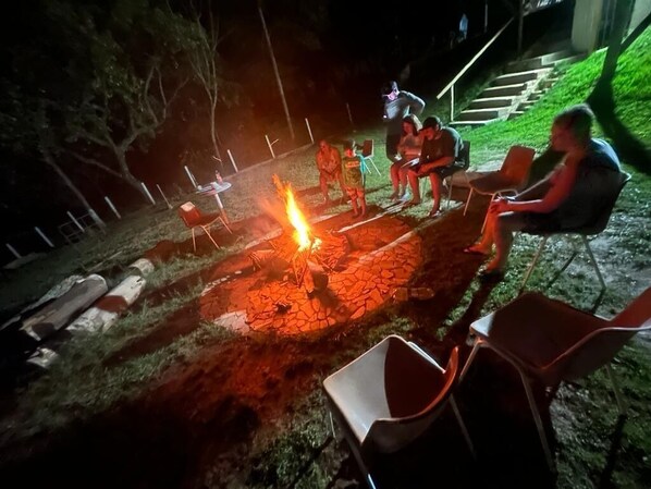 Un groupe de personnes assises autour d’un feu de camp, la nuit.