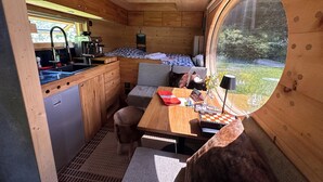 A compact kitchen with a sink, coffee machine, and a dining area with a table and bench. - Zinipi Lodge at the Oldtimer near Amberg (Ursensollen)