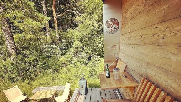 A wooden deck with a table, chairs, and a bottle of wine. - Zinipi Lodge at the Oldtimer near Amberg (Ursensollen)
