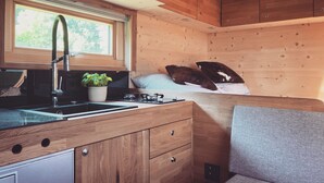 A compact kitchenette with a window, a sink, a stove, and a small cabinet. - Zinipi Lodge at the Oldtimer near Amberg (Ursensollen)